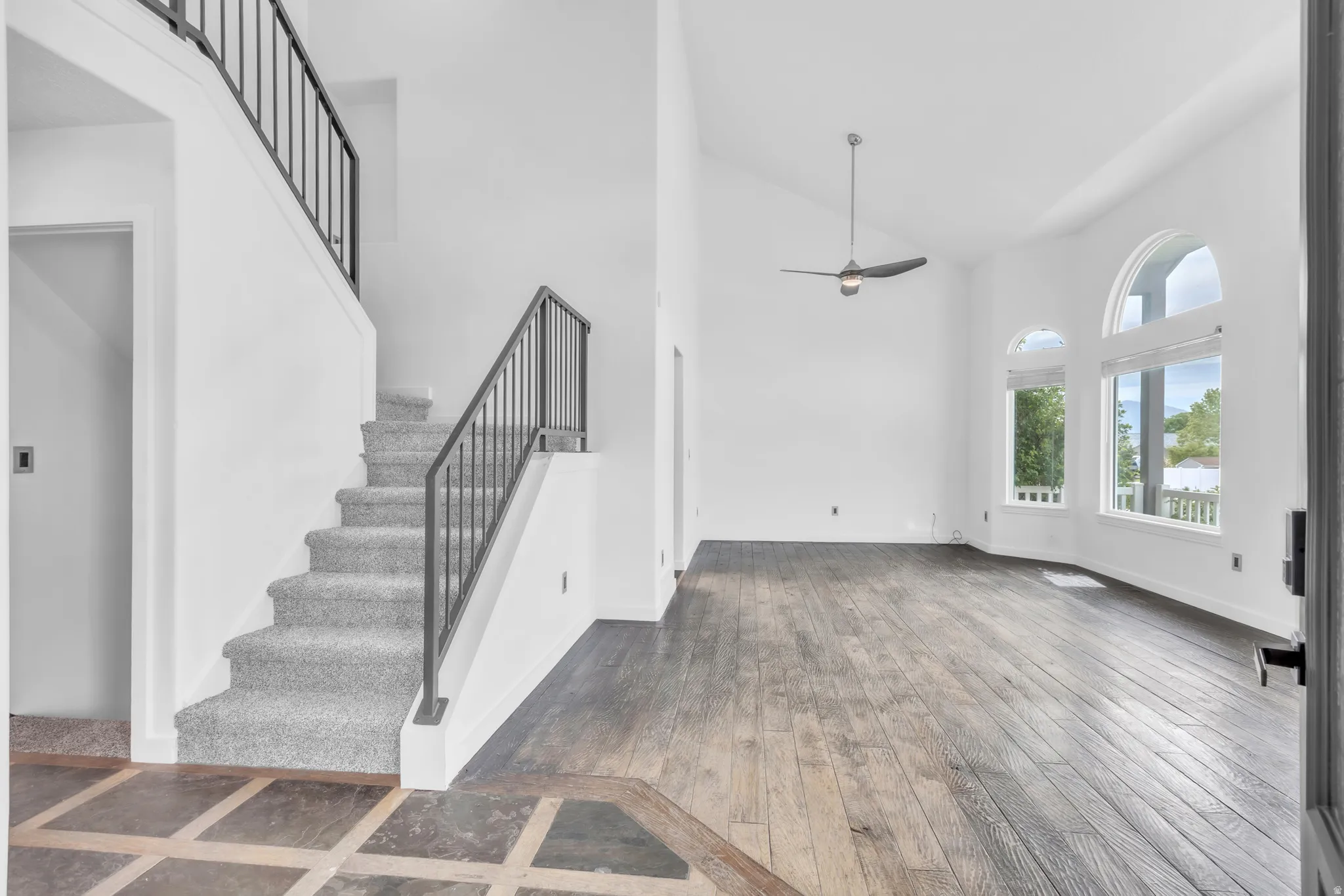 Spacious entry with tile flooring, featuring a staircase with carpeted treads and metal railings