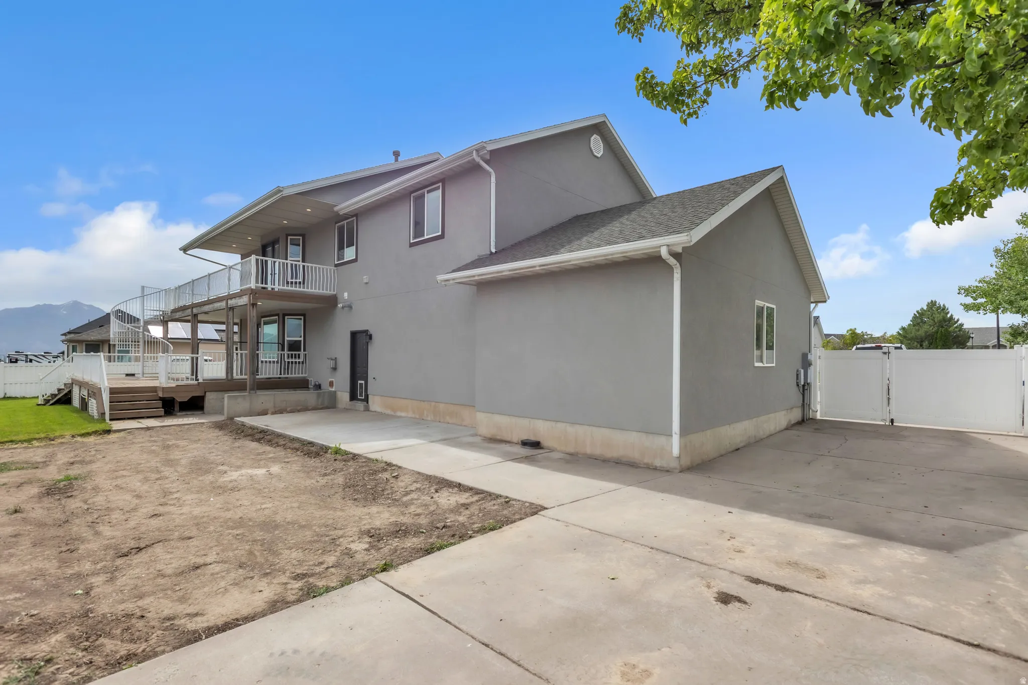 Multi-level exterior featuring a stucco finish, dual-level deck with white railings, and a spiral staircase