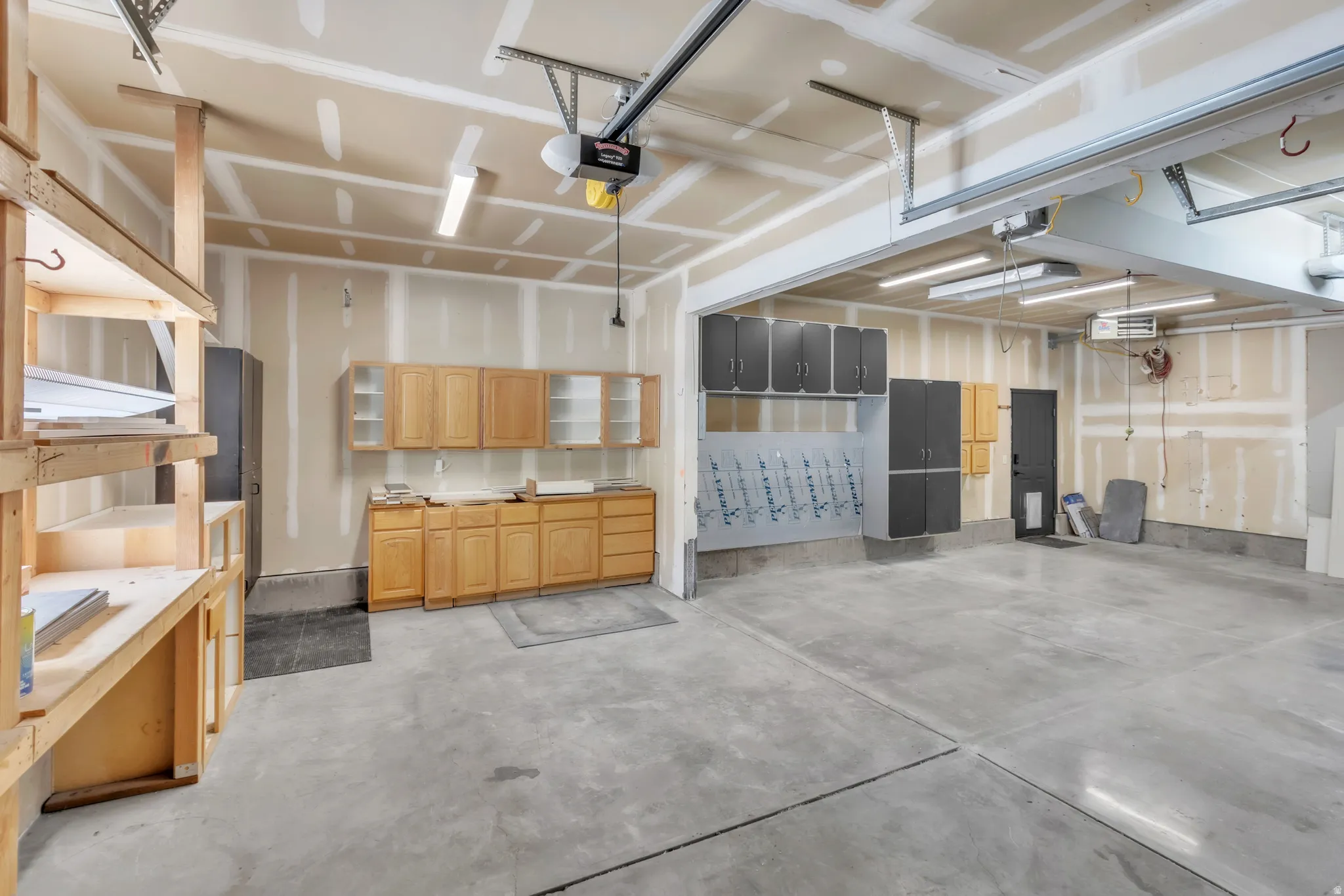 Spacious garage with concrete flooring, natural wood-finish cabinetry, built-in shelving, and overhead lighting