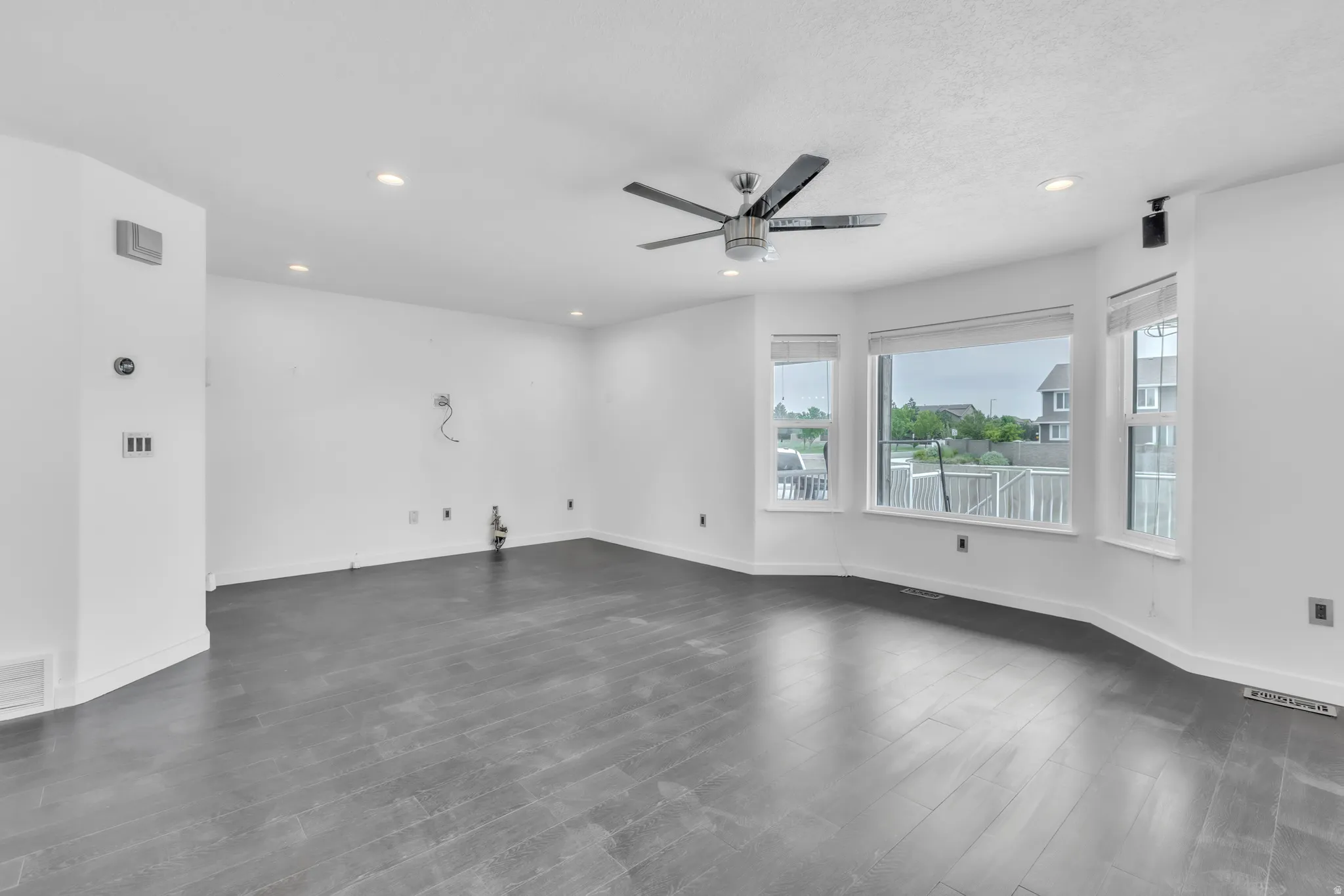 Spacious room featuring dark wood-finish flooring, recessed lighting, and a modern ceiling fan