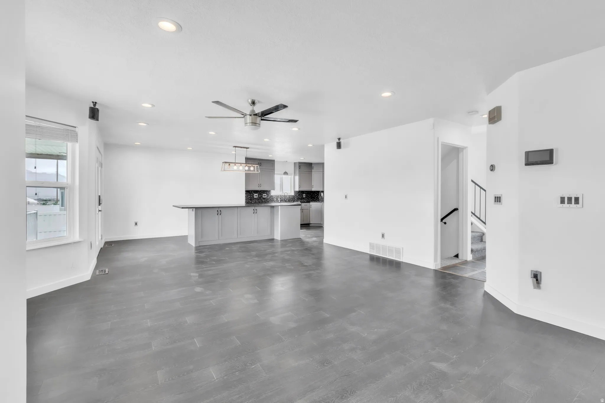 Open-concept living area featuring dark wood-finish flooring, white walls, and recessed lighting