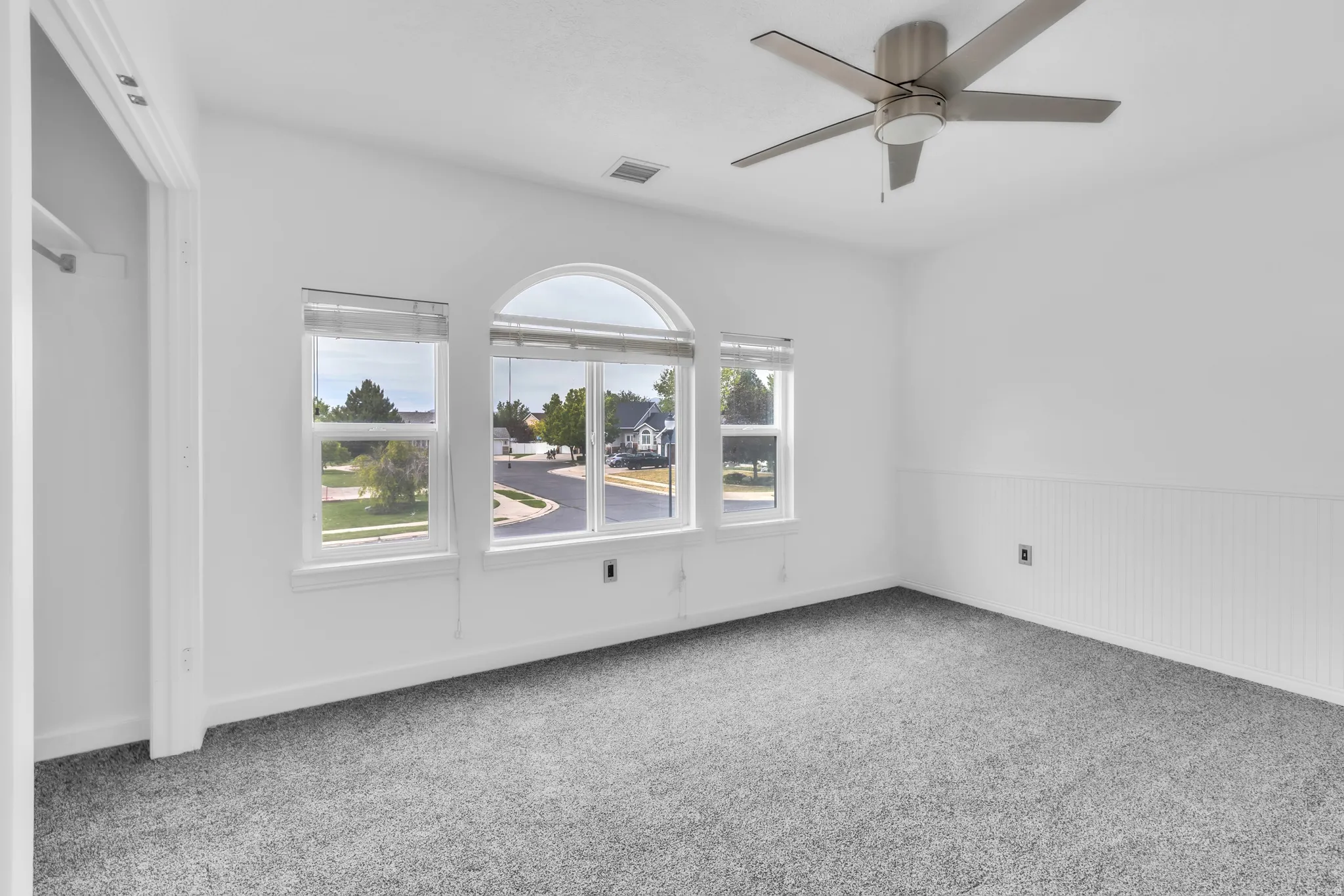 Triple window bank featuring an arched transom and white window treatments