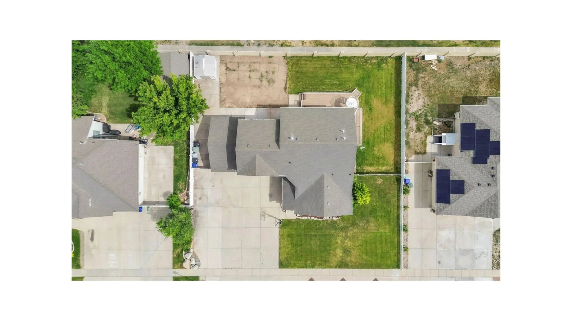 Expansive property featuring a multi-gabled roofline, concrete driveway, and a combination of manicured lawn and undeveloped land