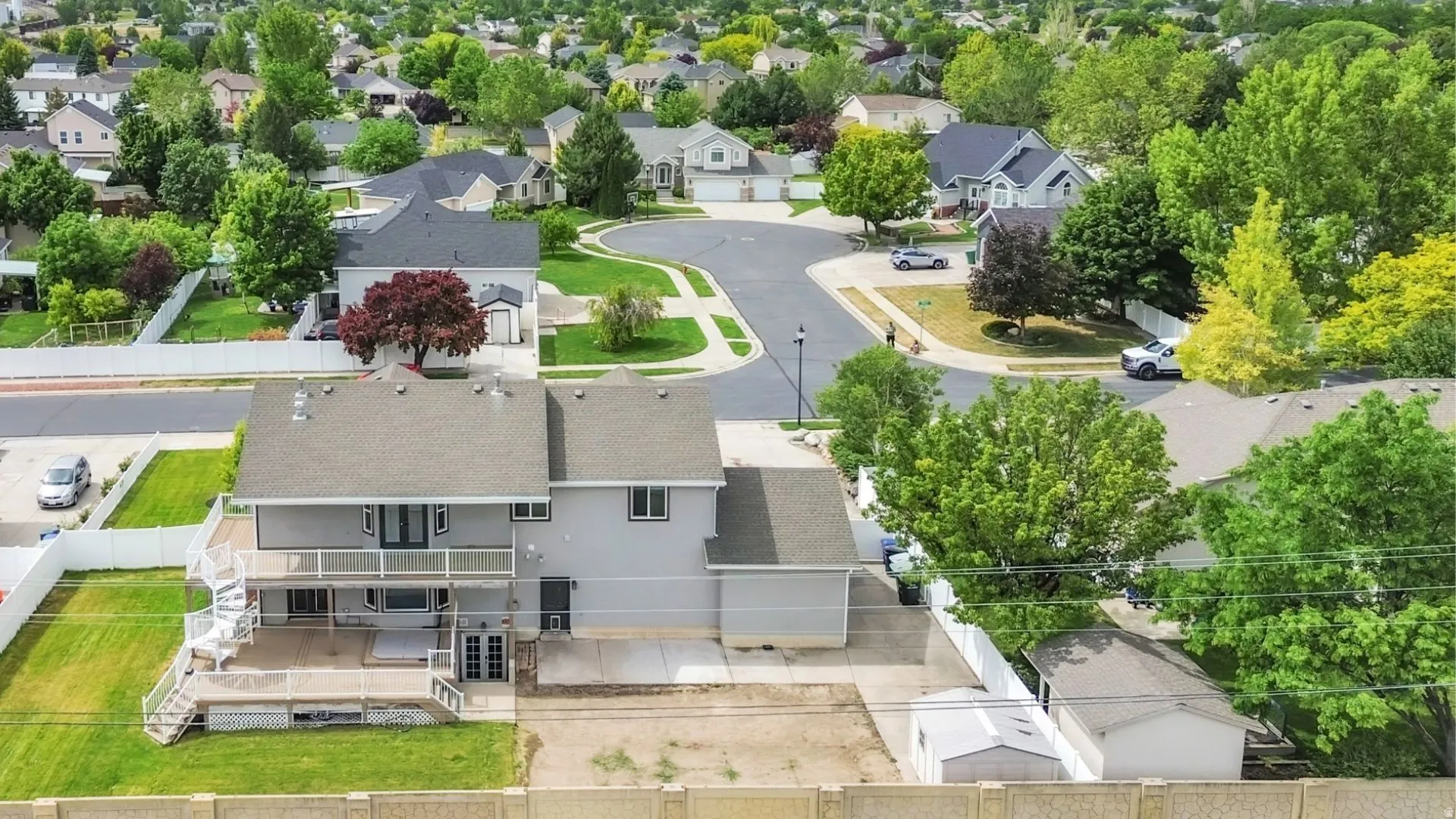 Two-story residence featuring a second-level deck with white railings and spiral staircase access