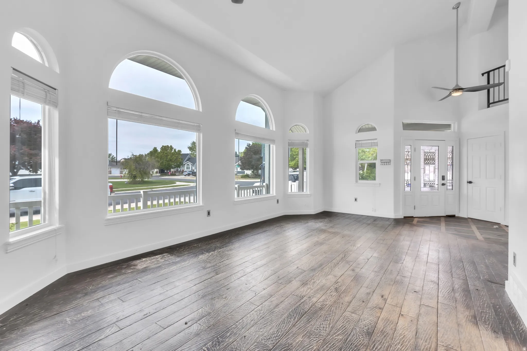 Spacious living area featuring high vaulted ceilings, multiple arched windows, and dark wood-finish flooring