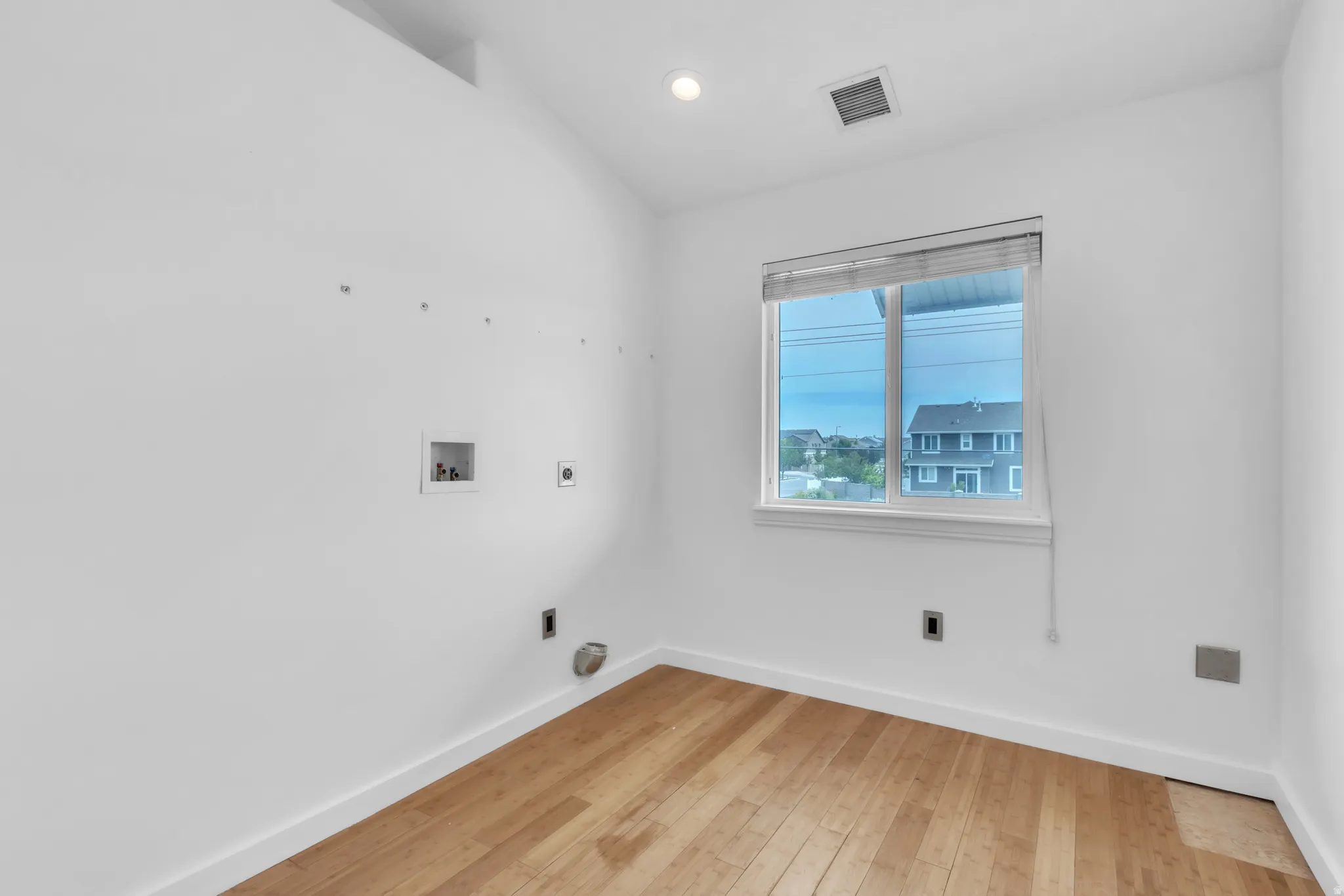 Secondary laundry room featuring wood-finish flooring, a window with blinds, and recessed lighting