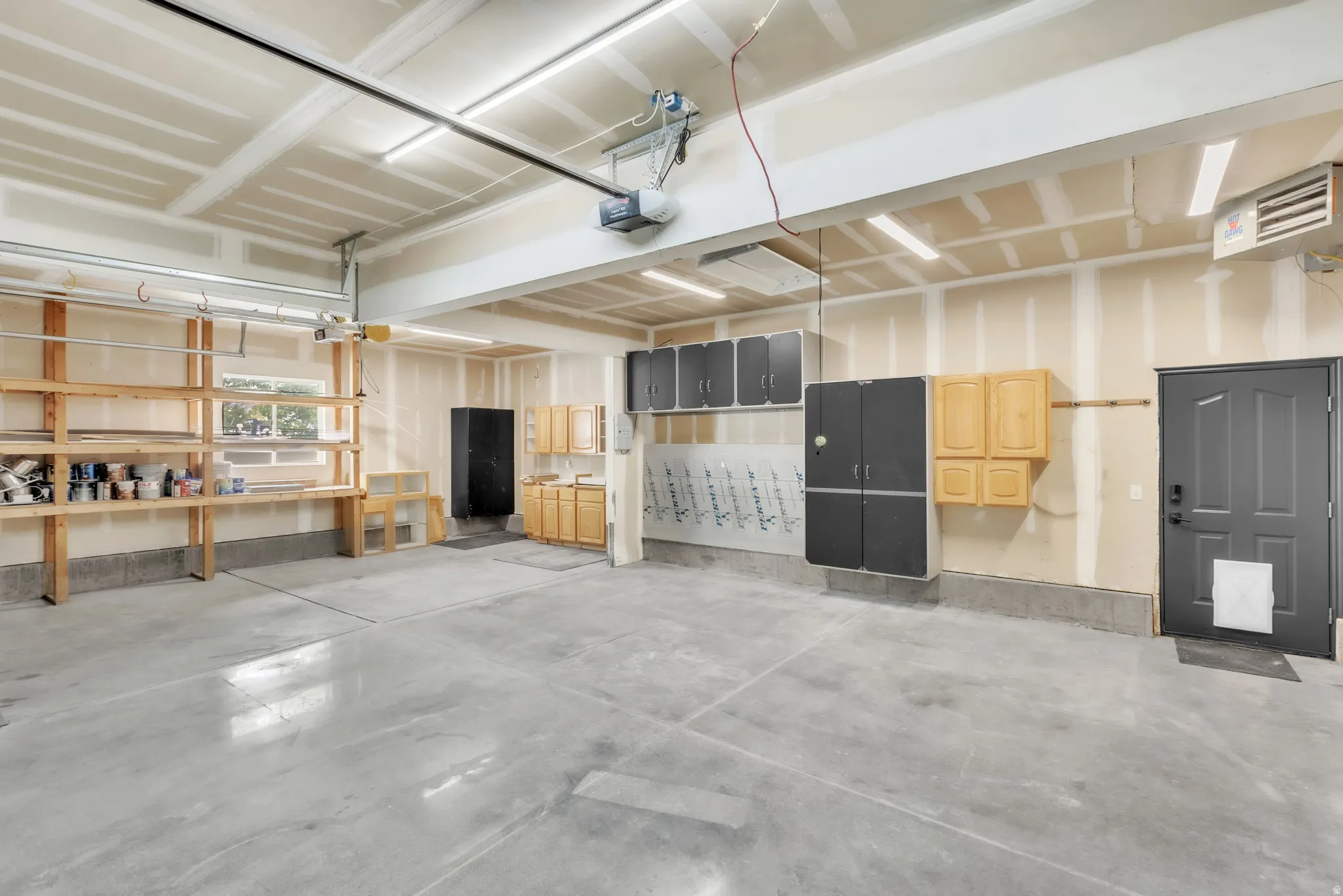 Spacious garage featuring a concrete floor, built-in shelving, various cabinetry for storage, and a single window for natural light
