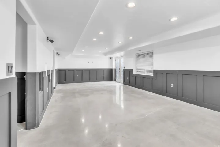 Spacious room featuring board and batten wainscoting, polished concrete flooring, recessed lighting, and a window with blinds