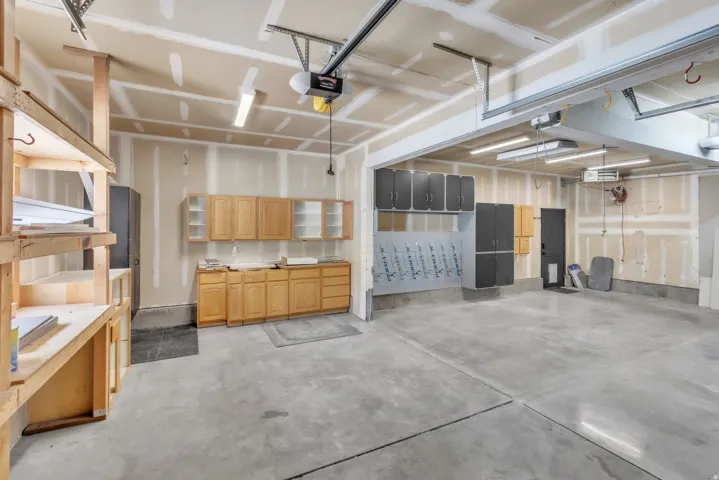 Spacious garage with concrete flooring, natural wood-finish cabinetry, built-in shelving, and overhead lighting