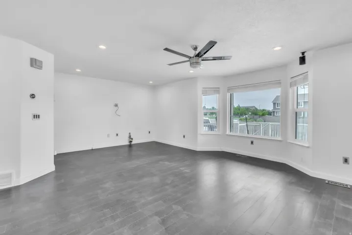 Spacious room featuring dark wood-finish flooring, recessed lighting, and a modern ceiling fan