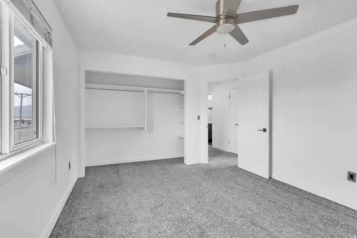 Bedroom featuring gray carpet, a ceiling fan with brushed nickel finish, and a window with white trim