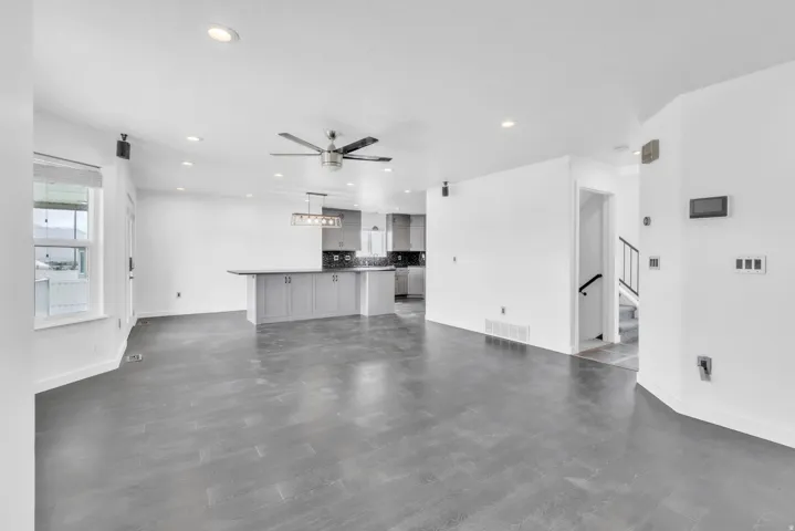 Open-concept living area featuring dark wood-finish flooring, white walls, and recessed lighting