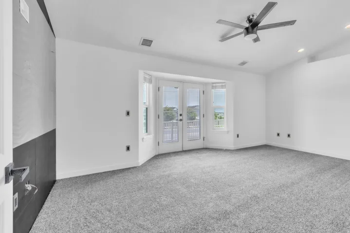 Primary bedroom featuring light gray carpeting, a contemporary ceiling fan, recessed lighting, and a bay window with double doors leading to an exterior balcony