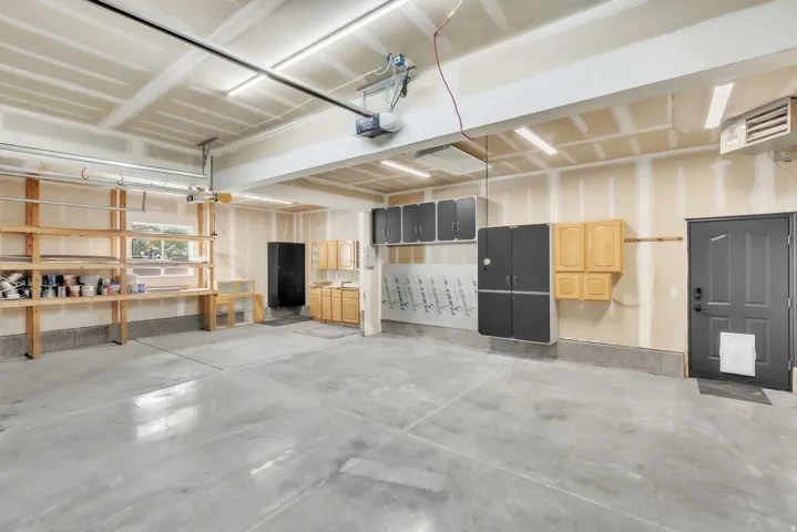 Spacious garage featuring a concrete floor, built-in shelving, various cabinetry for storage, and a single window for natural light