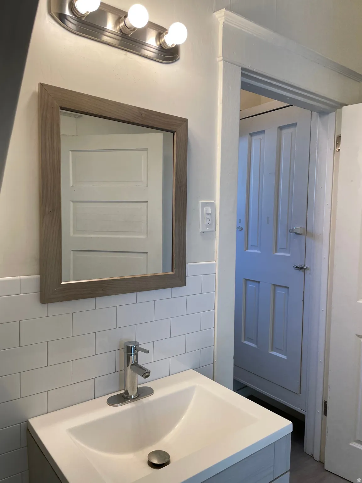 Bathroom vanity featuring a white integrated sink, chrome single-handle faucet, and wood-frame mirror