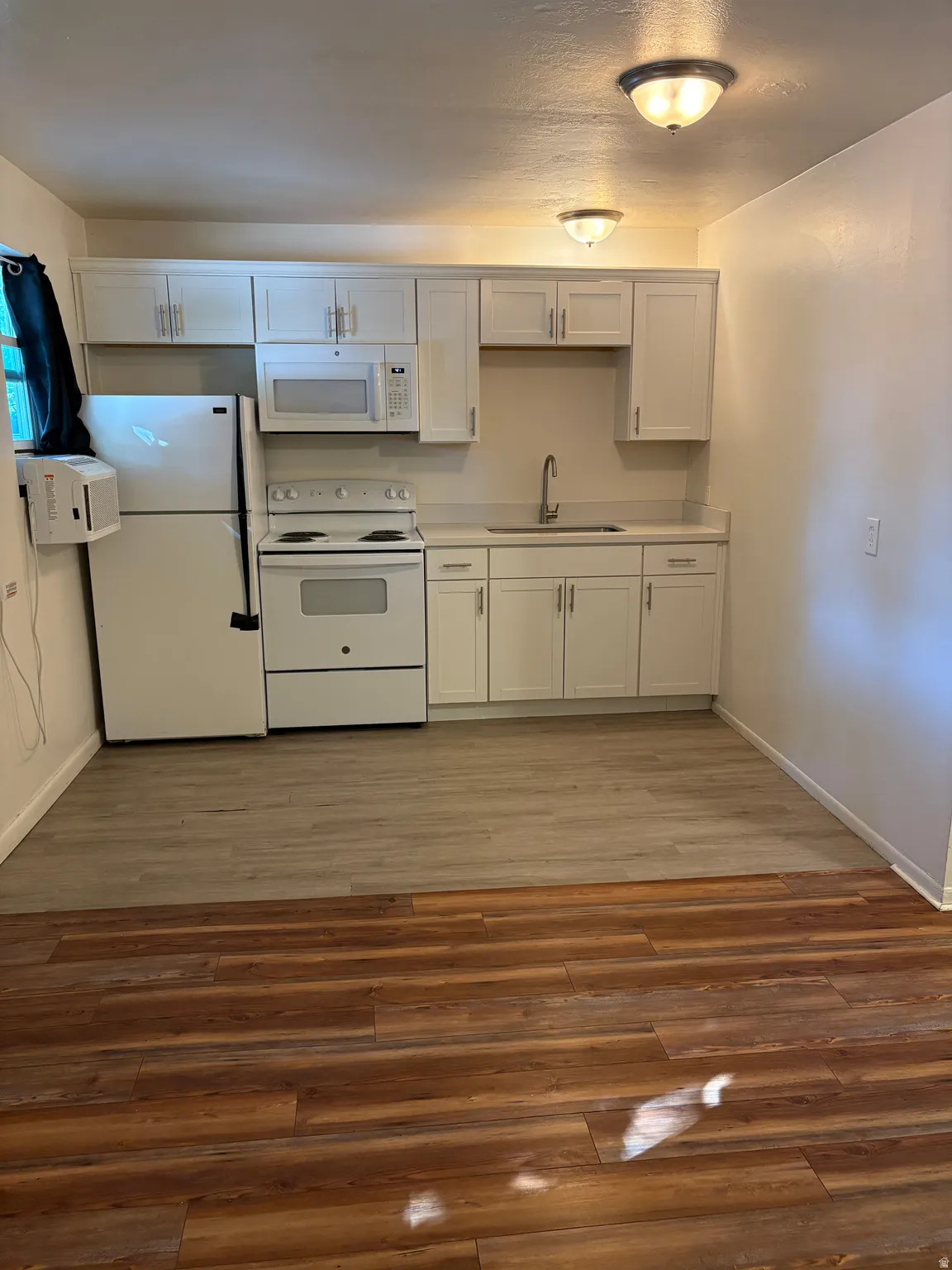 Kitchen area featuring white cabinetry, white appliances, and light-toned countertops