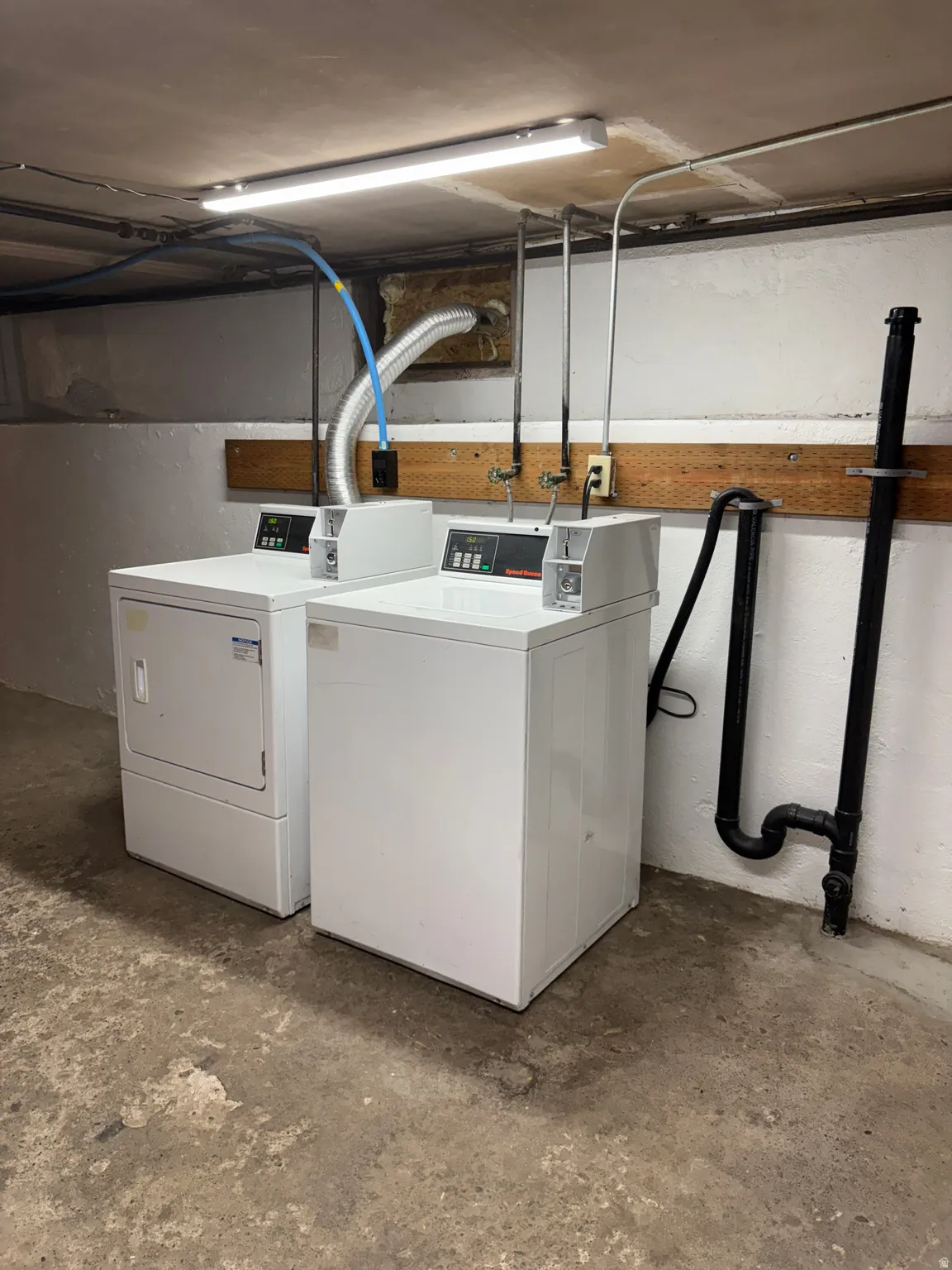 Dedicated laundry area featuring a washer and dryer, concrete flooring, and exposed utility piping