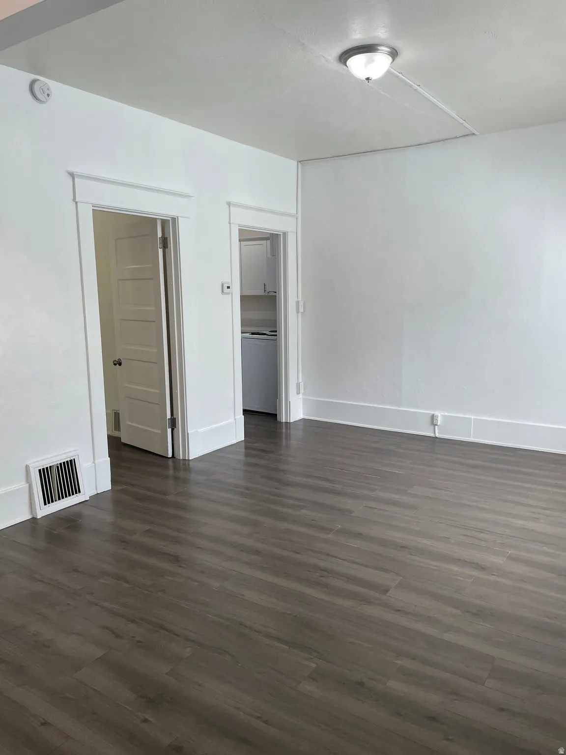 Spacious interior featuring wood-finish flooring, white walls, and a ceiling-mounted light fixture