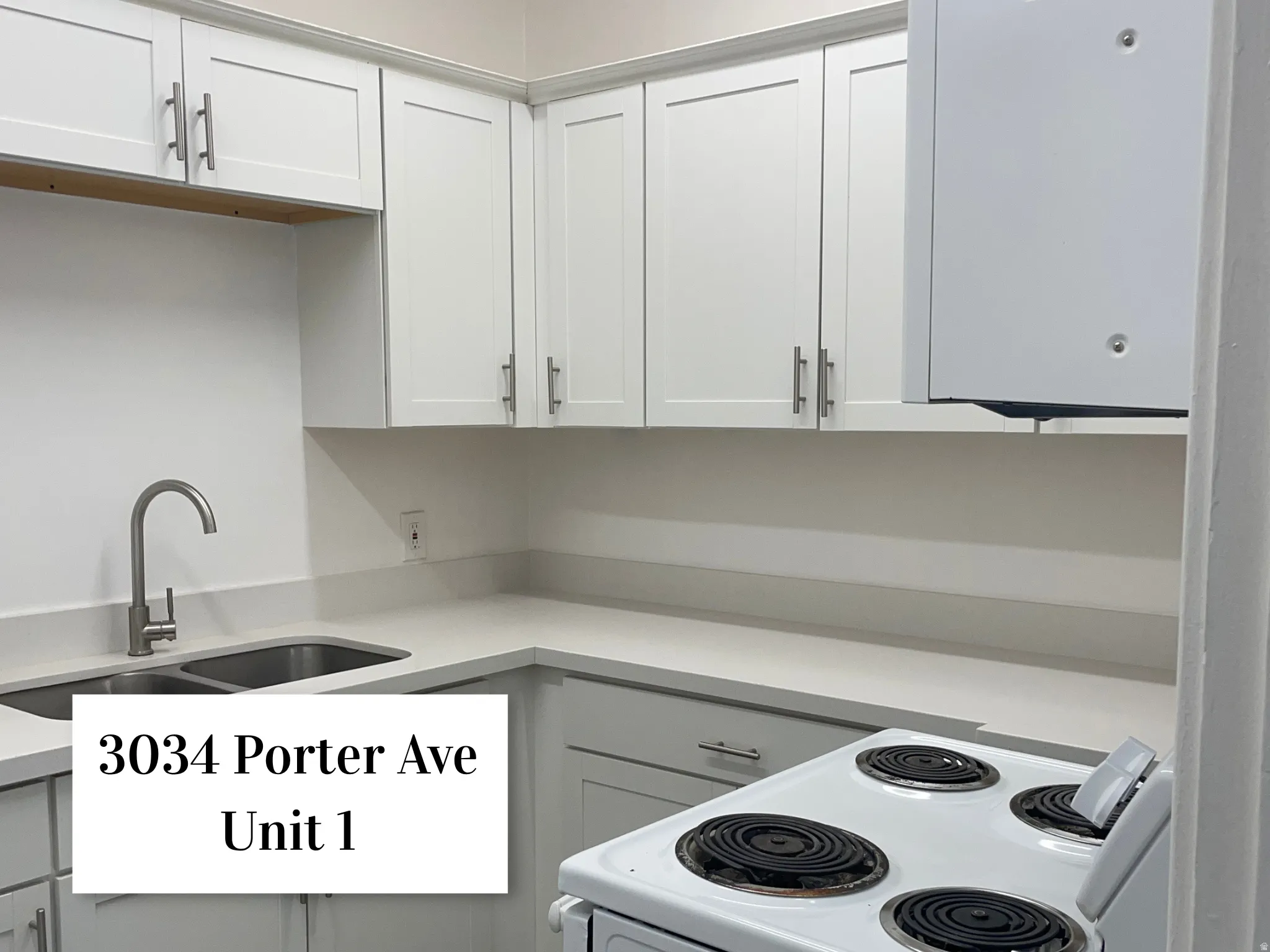 Modern kitchen featuring white shaker cabinetry, stainless steel hardware, a double basin sink with a gooseneck faucet, light-toned countertops, and a white electric range