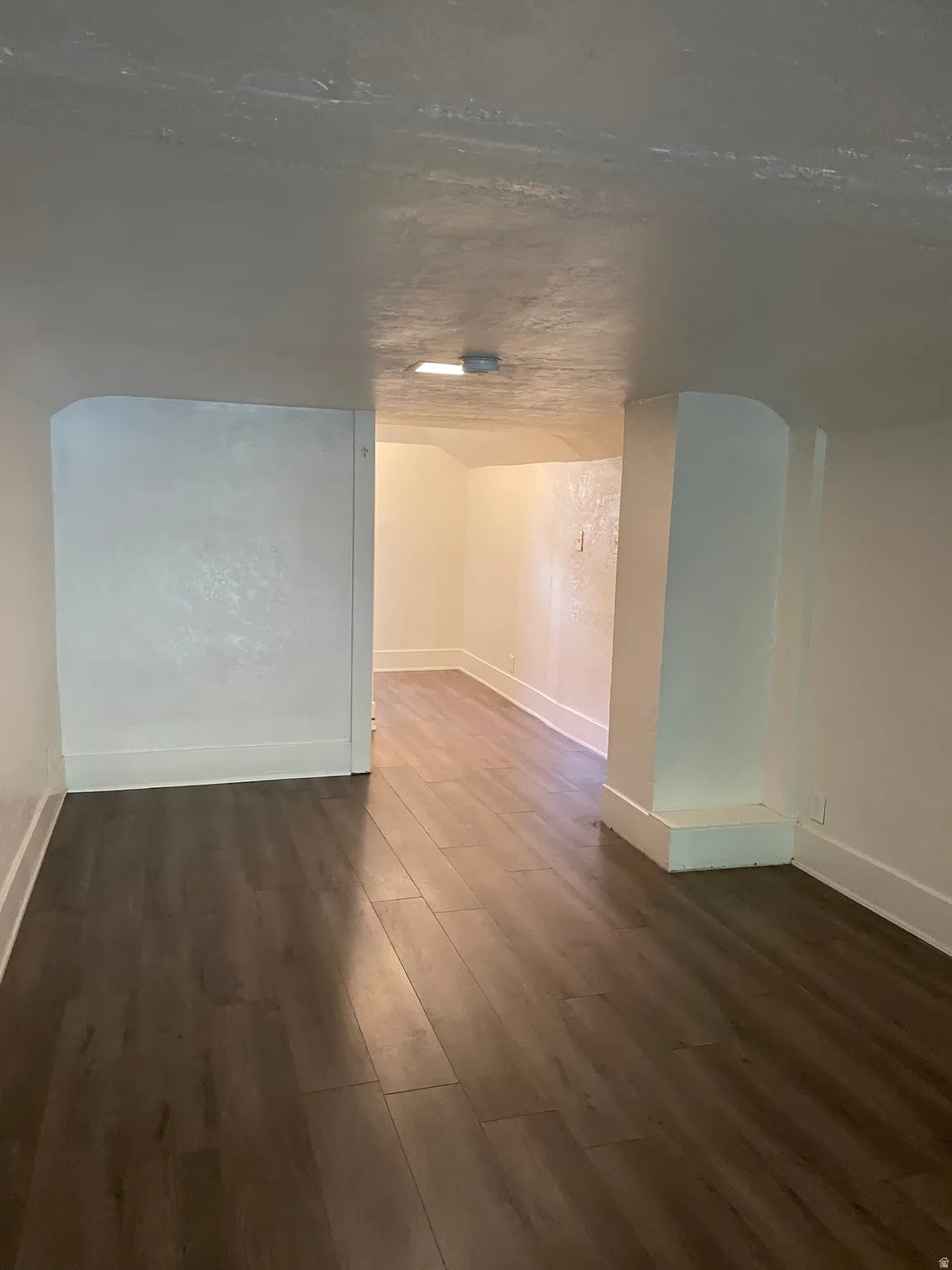Interior space featuring dark wood-finish flooring, white baseboards, and white painted walls