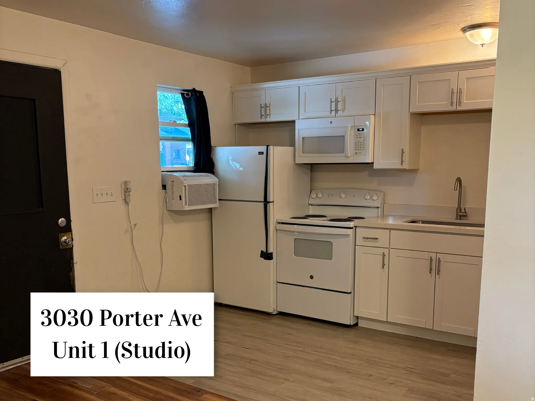 Updated kitchen area featuring light wood-finish flooring, white cabinetry with silver hardware, a white oven/stove, a white refrigerator, and a stainless steel sink with a gooseneck faucet