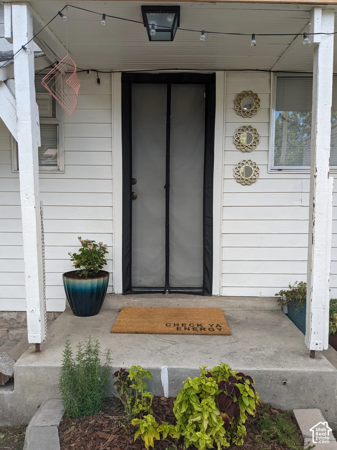 Entryway featuring white horizontal siding and a black-framed screen door