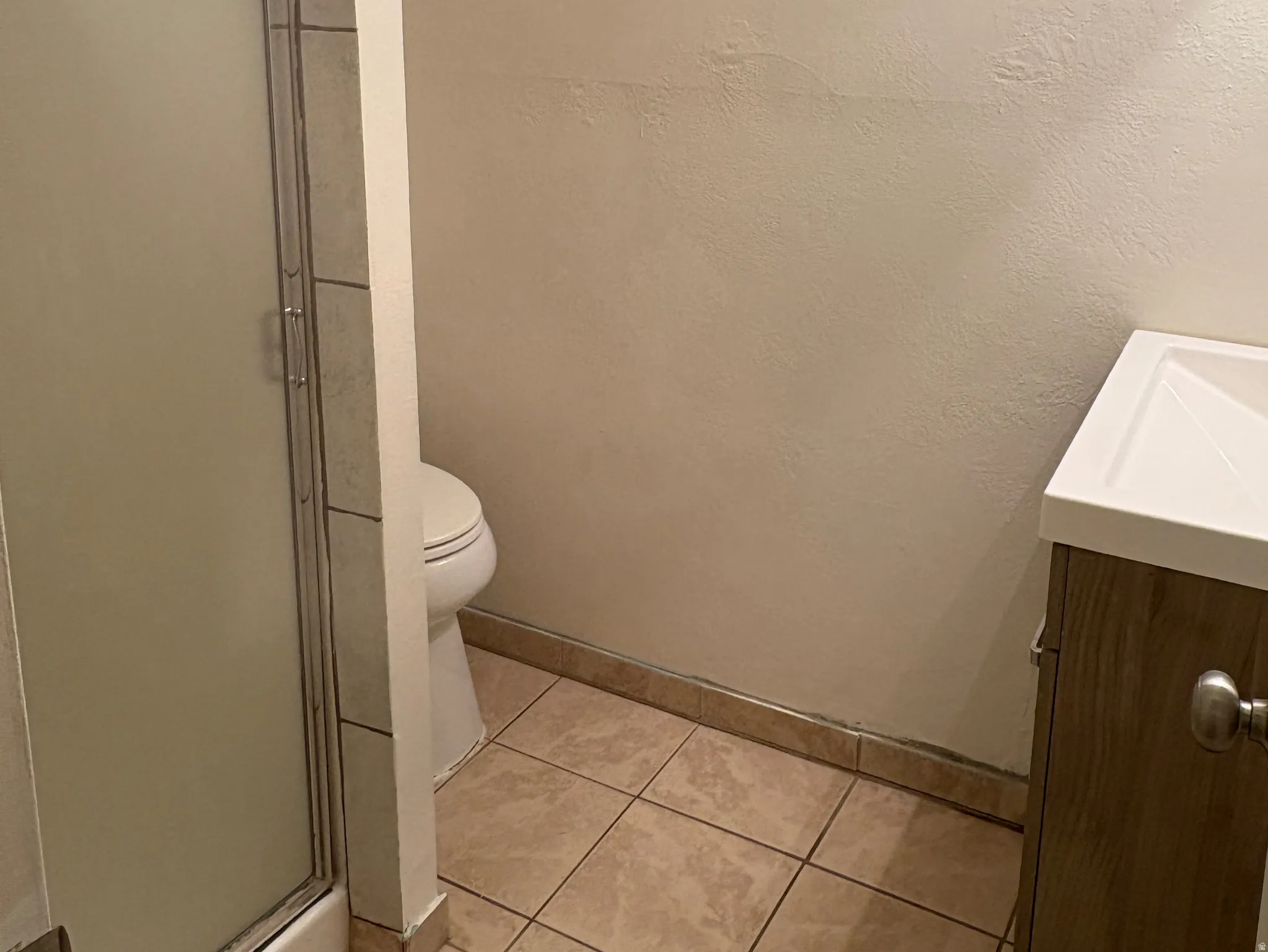 Compact bathroom featuring a shower with a sliding glass door, a white toilet, and a vanity with a rectangular basin