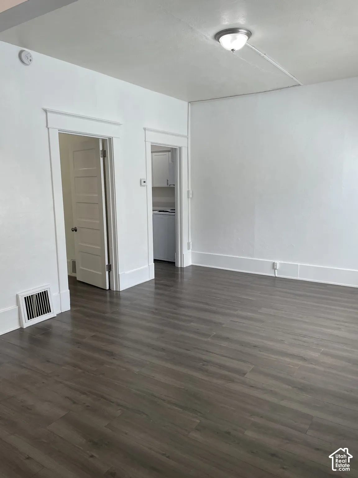 Spacious interior featuring wood-finish flooring, white walls, and a ceiling-mounted light fixture