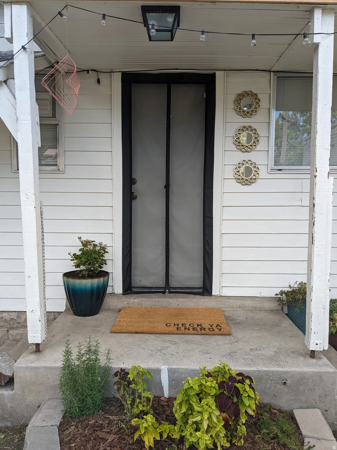 Entryway featuring white horizontal siding and a black-framed screen door