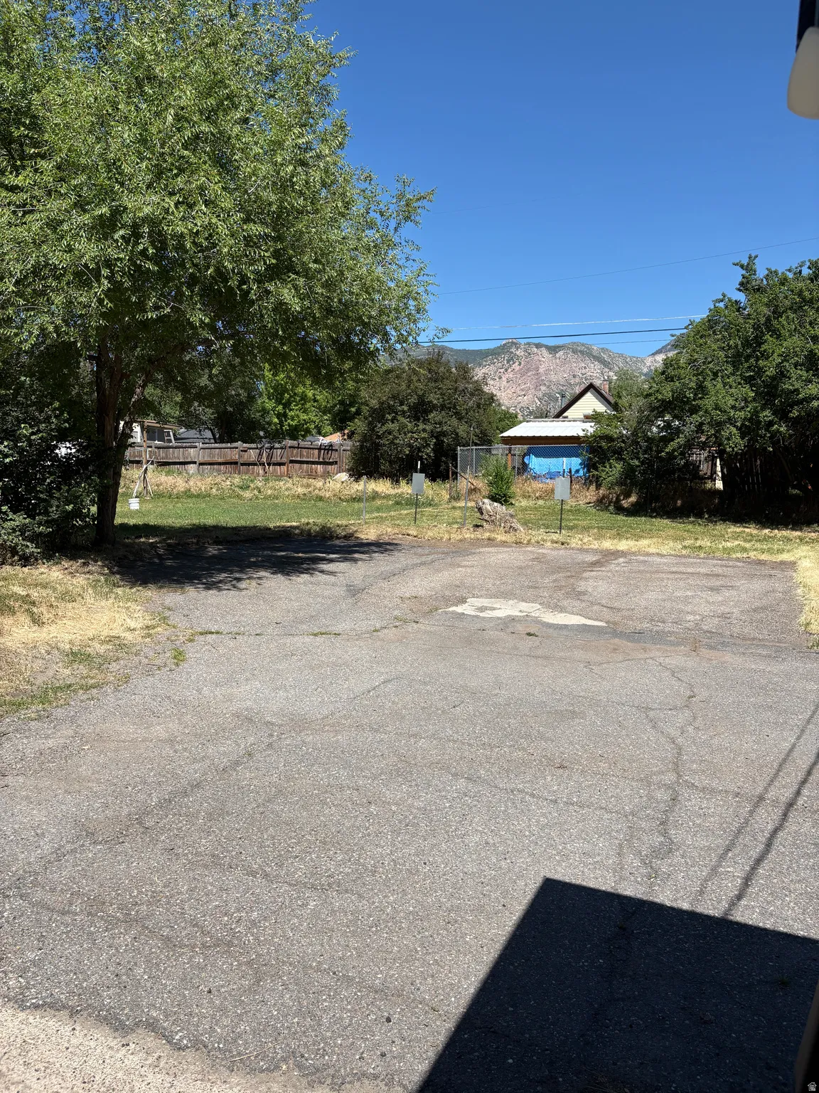 Paved surface area with mature trees and a distant mountain backdrop