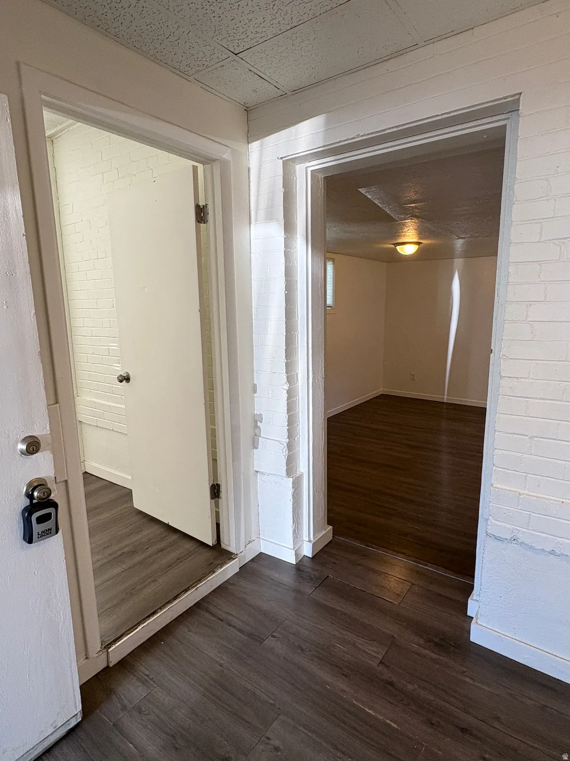 Entryway featuring wood-finish flooring, white painted brick walls, and access to additional rooms