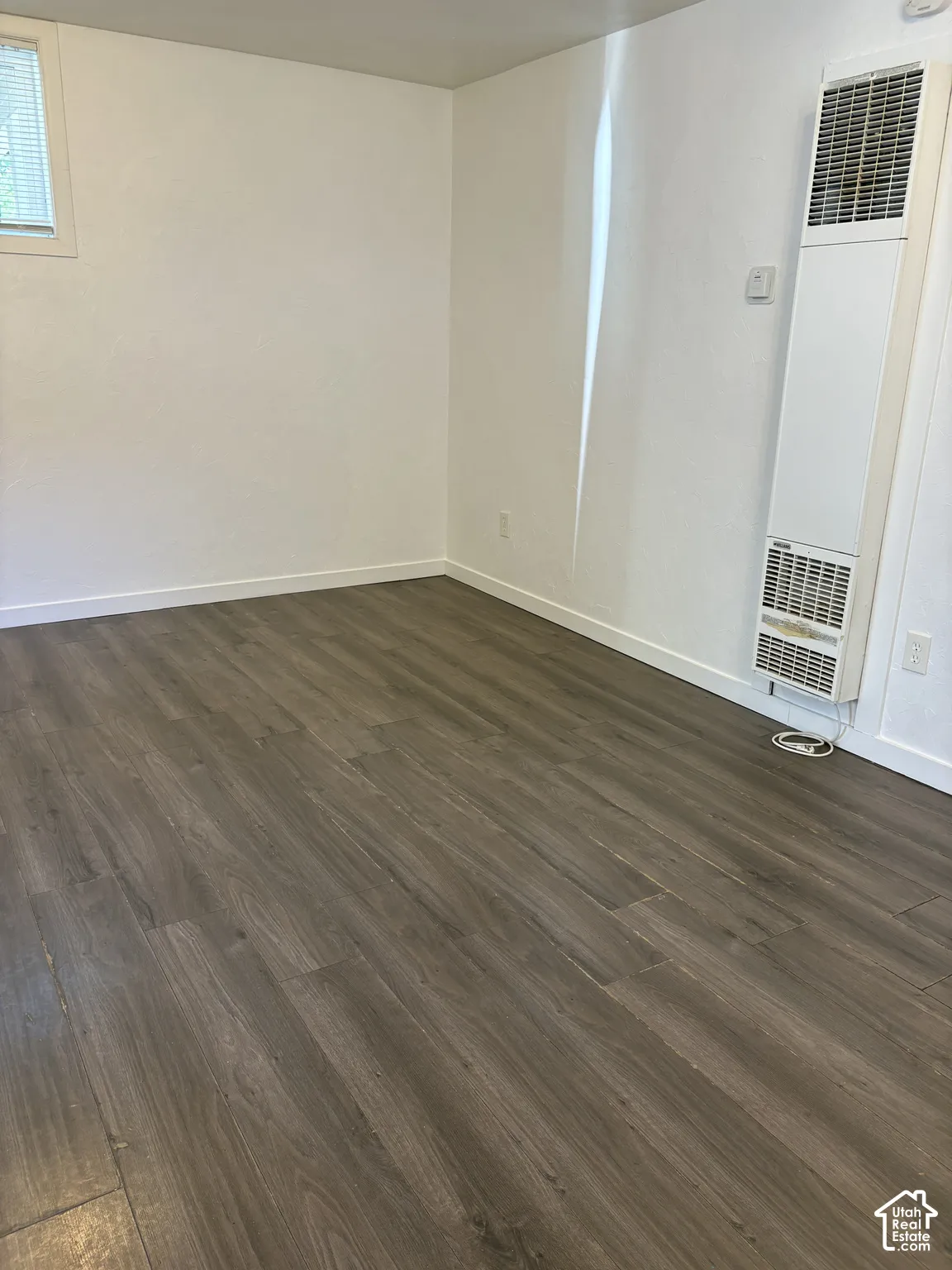 Spacious interior featuring wood-finish flooring, white baseboards, and a window with horizontal blinds