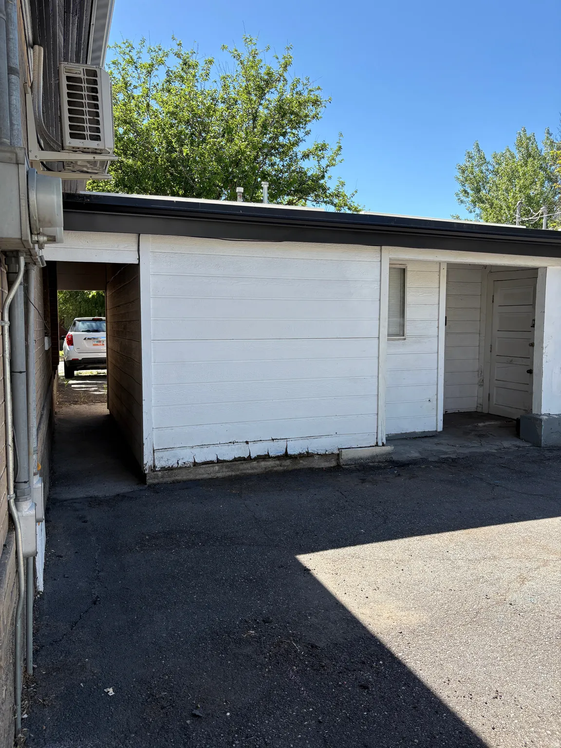 White horizontal siding exterior with black trim, a covered entryway, and asphalt paving