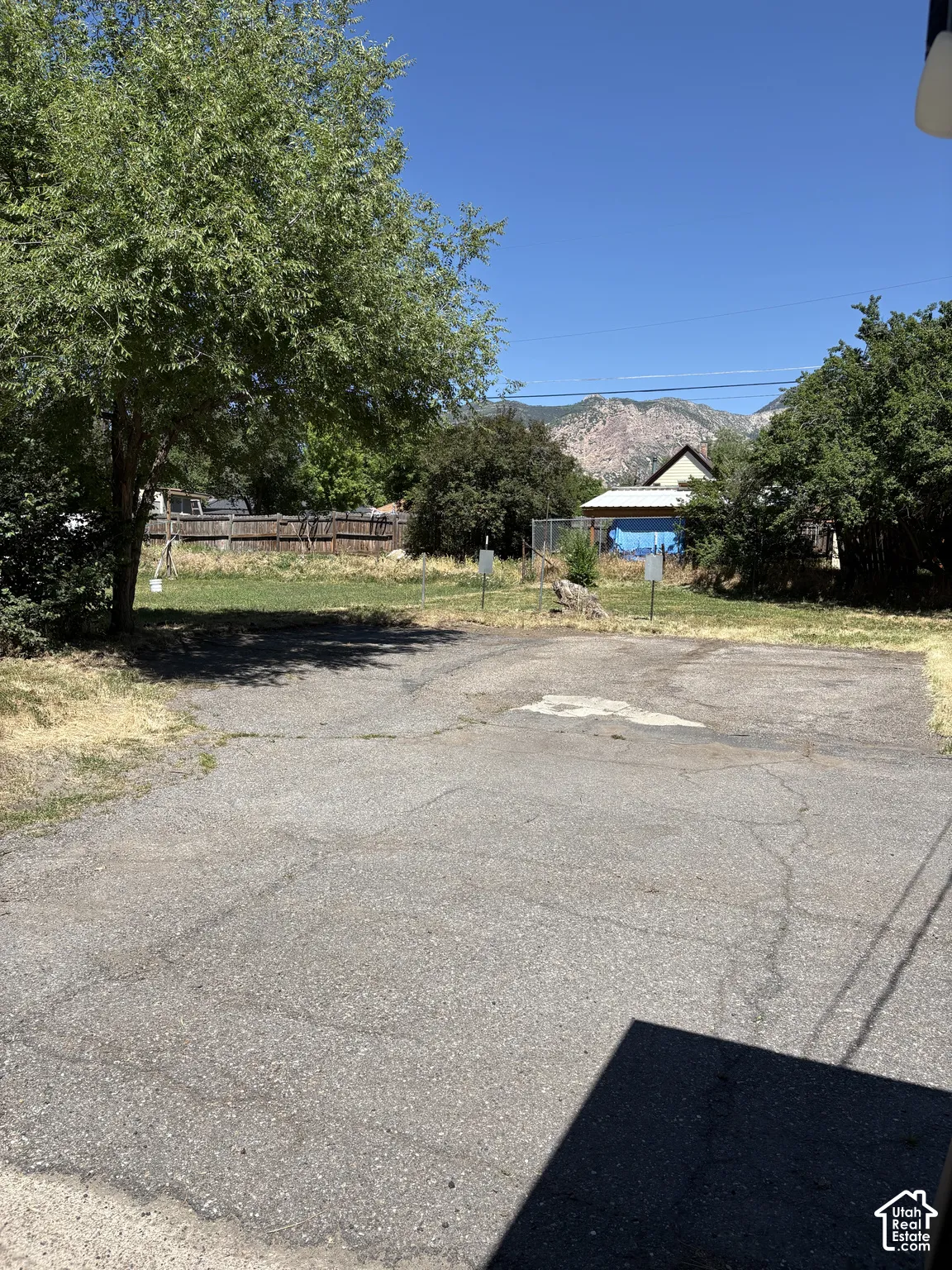 Paved surface area with mature trees and a distant mountain backdrop