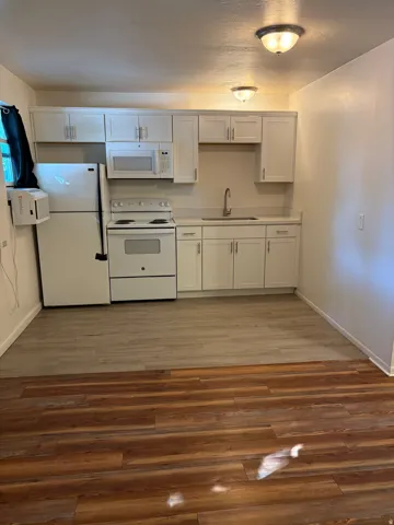 Kitchen area featuring white cabinetry, white appliances, and light-toned countertops