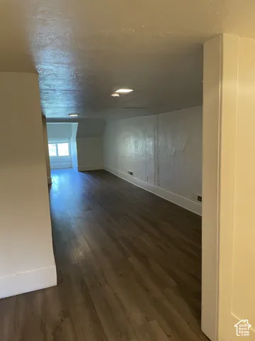 Spacious room featuring wood-finish flooring, white painted walls, recessed lighting, and a large window