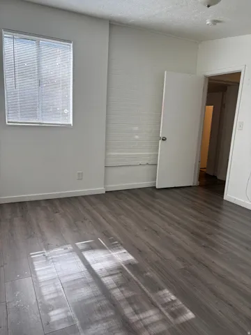 Wood-finish flooring throughout, featuring a white painted brick accent wall