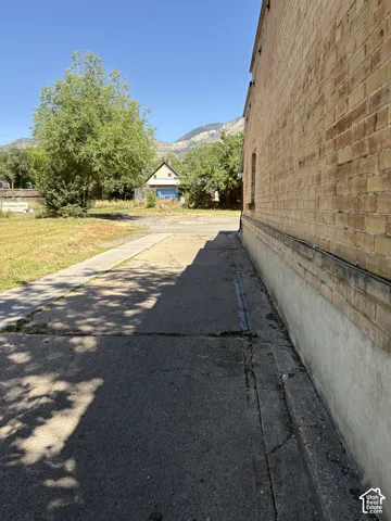 Brick exterior with concrete foundation, featuring a paved pathway and an expansive grassy area