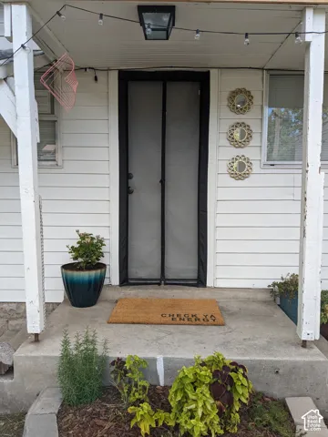 Entryway featuring white horizontal siding and a black-framed screen door