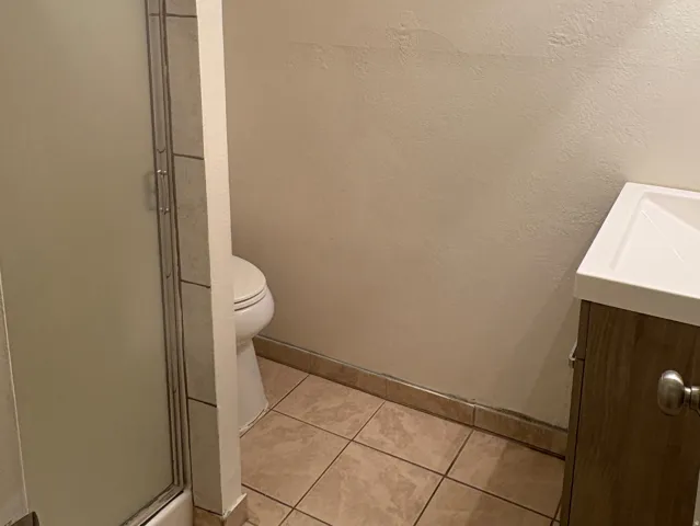Compact bathroom featuring a shower with a sliding glass door, a white toilet, and a vanity with a rectangular basin
