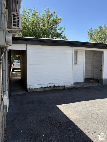 White horizontal siding exterior with black trim, a covered entryway, and asphalt paving