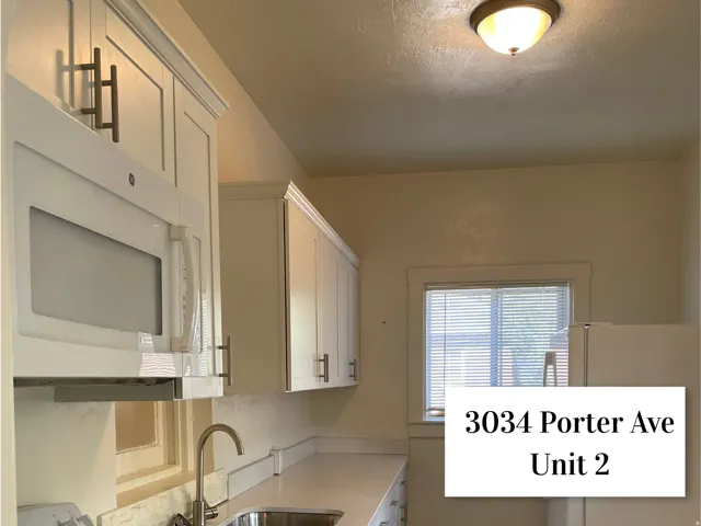 Kitchen featuring white cabinetry with dark pulls, white countertop, stainless steel sink, and a built-in microwave