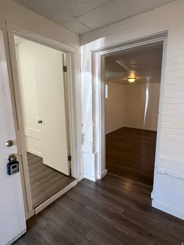 Entryway featuring wood-finish flooring, white painted brick walls, and access to additional rooms