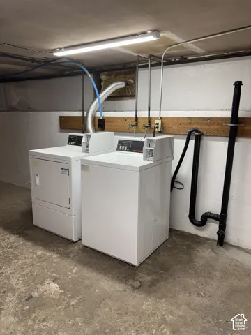Dedicated laundry area featuring a washer and dryer, concrete flooring, and exposed utility piping