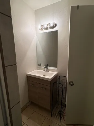 Bathroom vanity featuring a vessel sink, single-handle faucet, and wood-finish cabinetry with silver-tone pulls