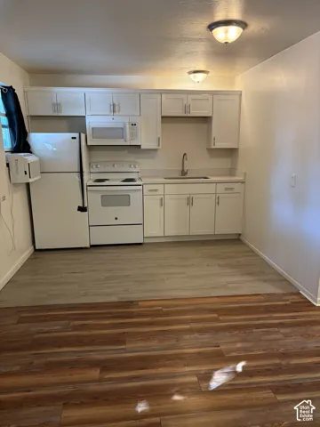 Kitchen area featuring white cabinetry, white appliances, and light-toned countertops