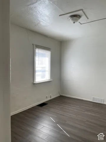 Room featuring wood-finish flooring, white walls, and a single window with blinds