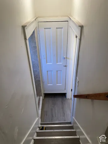 White paneled door with a privacy lock, wood-finish flooring, and light gray wall tiling