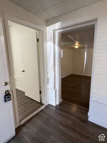 Entryway featuring wood-finish flooring, white painted brick walls, and access to additional rooms