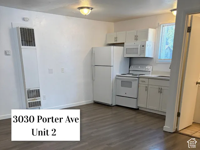 Kitchen area featuring white cabinetry with matching appliances, including a refrigerator, range, and microwave